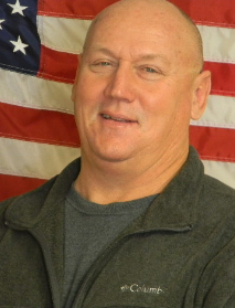 man in front of American flag wearing zip up jacket