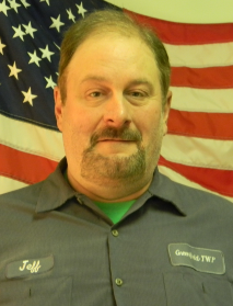 Man in front of American flag wearing blue button up shirt