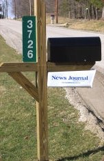 Green reflective address sign with the house number on a mailbox post